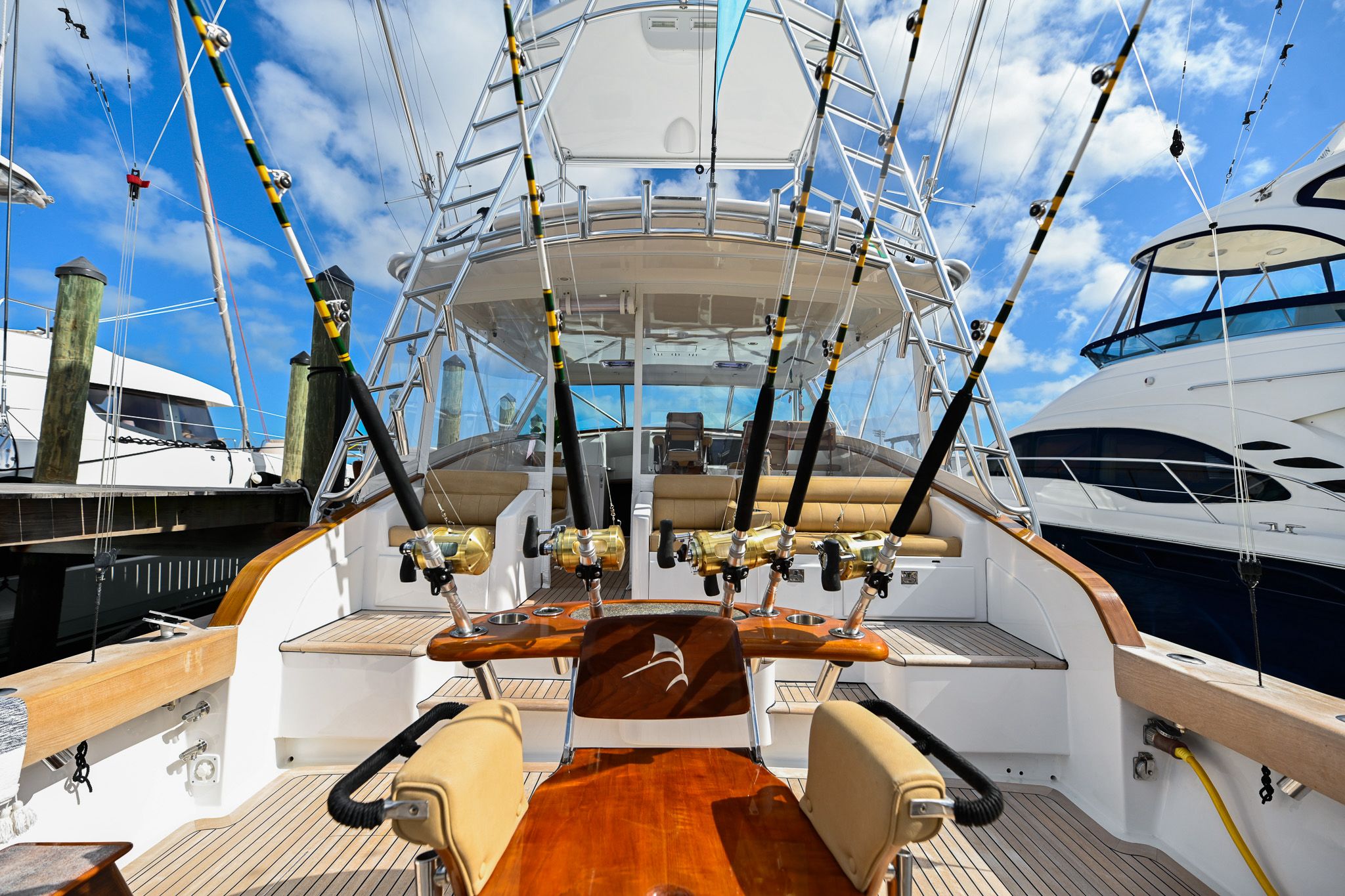The cockpit of a sportfishing yacht in its berth, with a fighting chair, teak decking and game rods in their holders